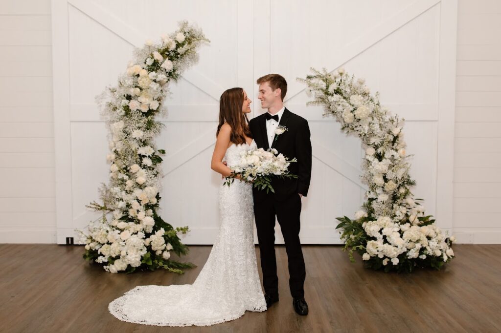 Kansas City wedding florist - Bride & Groom at wedding standing in front of a white floral arch