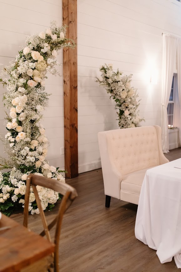 White floral arch behind sweetheart table at wedding reception