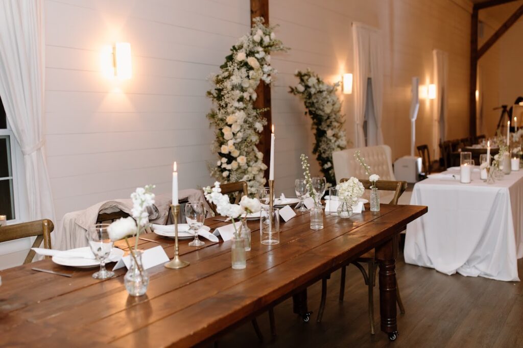 Kansas City wedding florist - Head table with bud vases and candles in front of white floral wedding arch