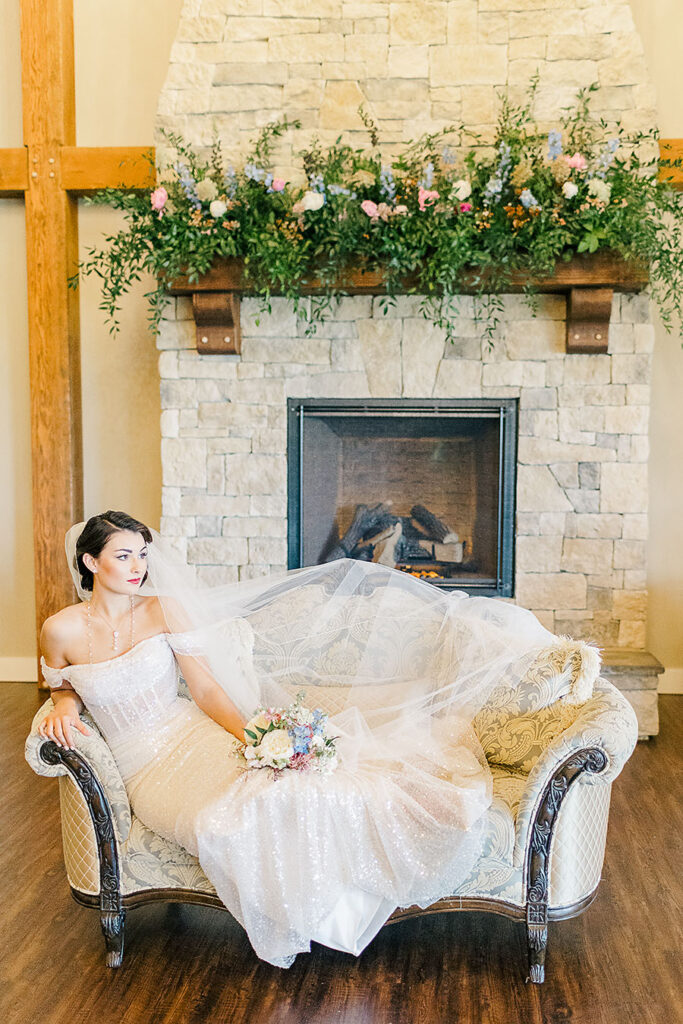 spring bride holding pastel bouquet in front of fireplace covered in flowers